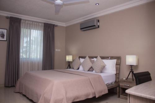 Manjaro Suites في آكرا: غرفة نوم بسرير كبير وتلفزيون