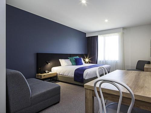 a hotel room with a bed and a table and chairs at Mantra MacArthur Hotel in Canberra