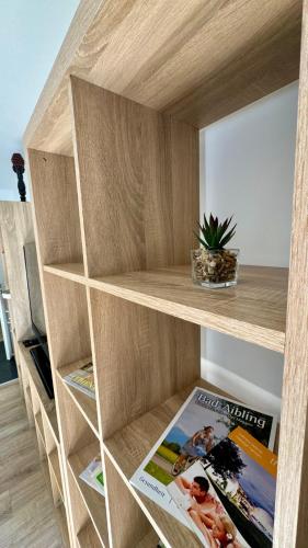 a book shelf with a magazine and a potted plant at Lindenhof Apartment 13 in Bad Aibling