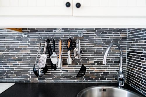 a kitchen counter with utensils hanging on a brick wall at Kåseberga Hideout in Kåseberga