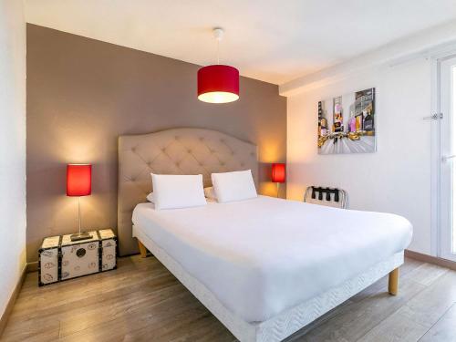 a bedroom with a large white bed with two lamps at Greet Hôtel Dijon Sud Longvic in Longvic