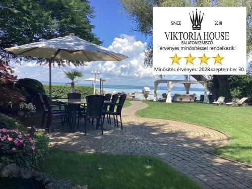 a table and chairs under an umbrella on a lawn at Viktoria House in Balatonszárszó