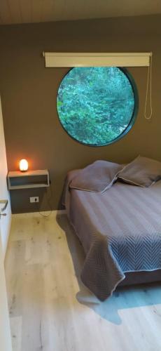 a bedroom with a round window in the wall at Vida en el bosque in Necochea
