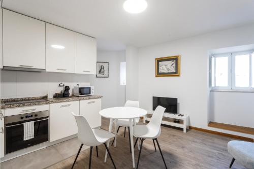 a kitchen with white cabinets and a table and chairs at Casa dos Barrett in Lisbon