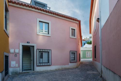a pink building with a door in a alley at Casa dos Barrett in Lisbon