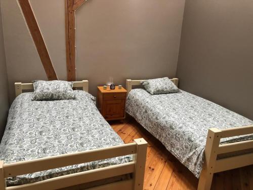two beds in a bedroom with a wooden floor at Krāģīši - Quiet Countryside aura in Rencēni