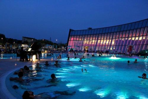 Un grupo de personas en una piscina por la noche. en Balconi sul Verde, en Pescantina