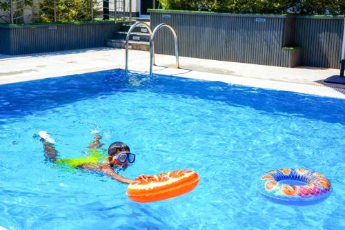 a person swimming in a swimming pool with two inflatables at Mabaat-White Pearl Compound 600 B Villa 9 in Jeddah