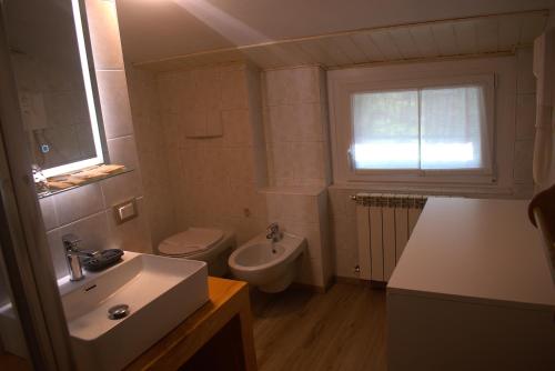 Un baño con lavabo, inodoro y ventana. en Casa Liscidini, en Aprica