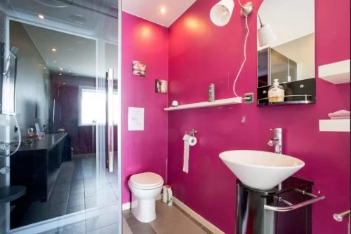 uma casa de banho rosa com um lavatório e um WC em Entertaining Studio em Wervik