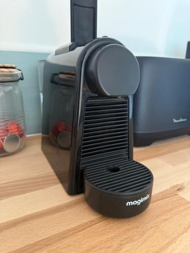 a black speaker sitting on the floor next to a microwave at OHANA Appartement de charme in Château-Gontier