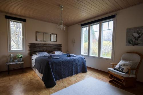 a bedroom with a bed and a chair and windows at Spacious detached house for a larger group in Rovaniemi