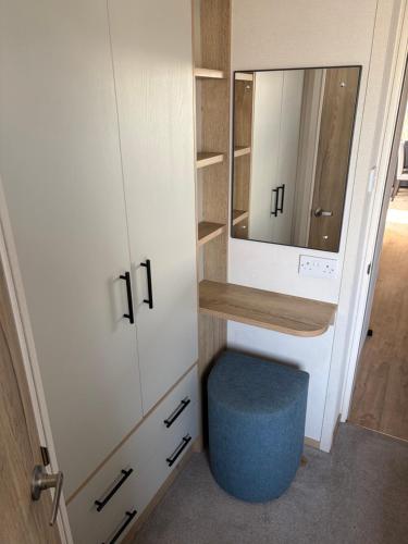 a small bathroom with a mirror and a blue stool at Driftwood dreams in Skipsea