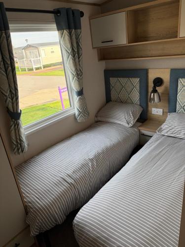 two beds in a small room with a window at Driftwood dreams in Skipsea