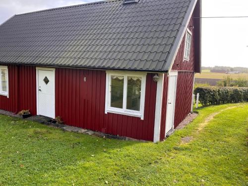 uma casa vermelha com um telhado cinza e um quintal em Bloms stuga i naturskön miljö em Falkenberg
