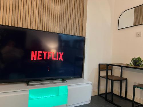 a flat screen tv sitting on top of a white cabinet at New Modern 3 Bed En-suites City Centre Apartment - Sleeps 8- Paid Parking Options in Preston