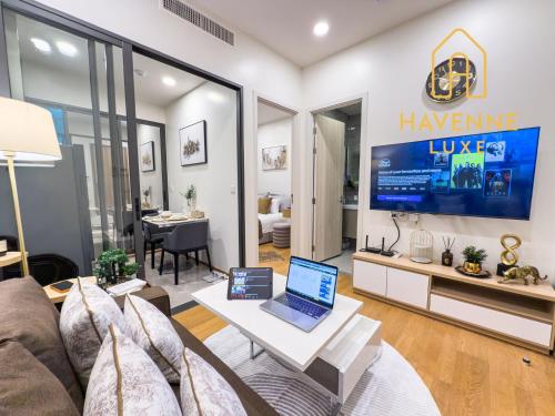 a living room with a couch and a laptop on a table at City Luxe Condo 5-Min Walk to Siam Paragon Modern Stay in Bangkok