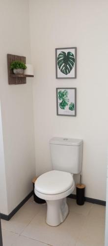 a bathroom with a toilet and three pictures on the wall at El refugio in La Paloma