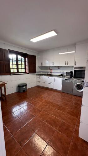 a large kitchen with white cabinets and a brown tile floor at Quinta de Carvalhal - Casa de Campo in Guimarães
