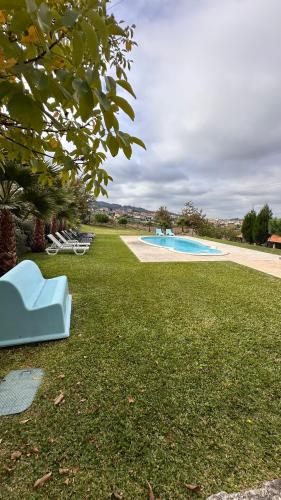 a blue chair sitting in the grass next to a pool at Quinta de Carvalhal - Casa de Campo in Guimarães