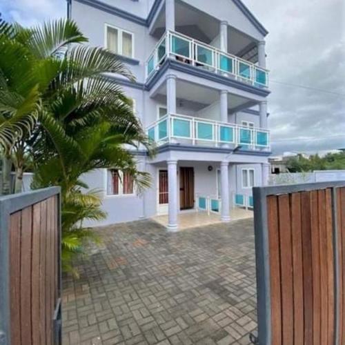 a large white building with a fence in front of it at Le Repos Blue Apartment in Pereybere