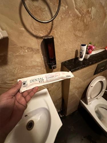 een persoon die een bordje boven een toilet in een badkamer houdt bij Bell Rooms Luxury studio Apartment in Noida