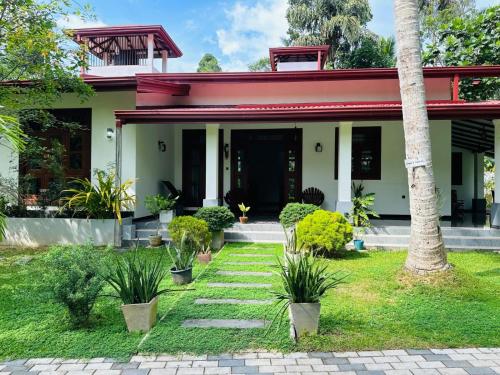 a house with a red roof and plants in the yard at The Garden Grove Villa in Yatiyana