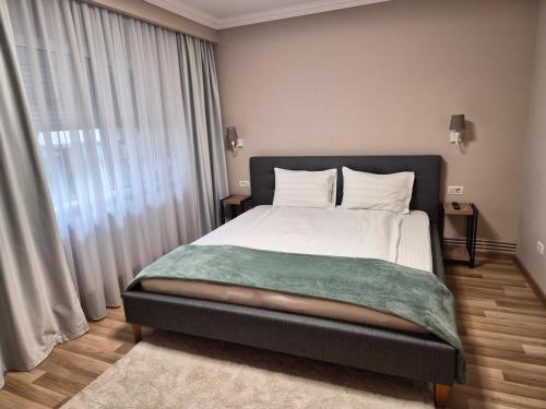 a bedroom with a bed with a green blanket on it at City Inn Premium Apartment in Timişoara