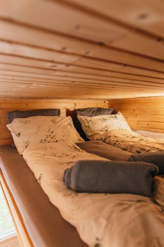 a bed in a wooden room with pillows on it at Krušnoglamp - Tinyhouse u Řeky in Sadov