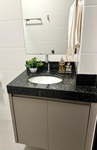 a bathroom sink with a black counter top at Studio Maia Aconchego e praticidade 190m da UFU in Uberlândia