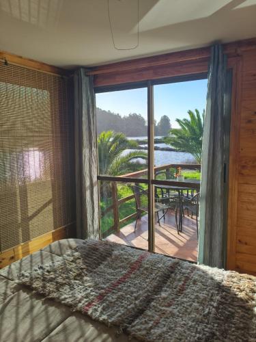 a bedroom with a bed and a balcony with a view at Cabaña en cahuil pichulemu in Cáhuil