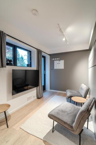 a living room with a tv and a couch and chairs at Staying Apt 6 in Tromsø