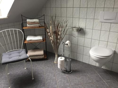 ein Badezimmer mit einem WC, einem Stuhl und Handtüchern in der Unterkunft Ferienwohnung Geli in Tönning
