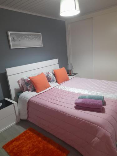 a bedroom with a large bed with pink and orange pillows at Encanto da Aldeia in Torre de Moncorvo