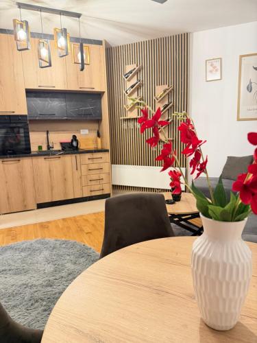 a vase with red flowers on a table in a kitchen at Prestige Forest Resort Zlatibor Wellness & Spa in Zlatibor