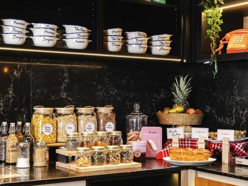 Mercure Reims Parc Des Expositions في رانس: كونتر مع جرار من الطعام وأصناف غذائية أخرى