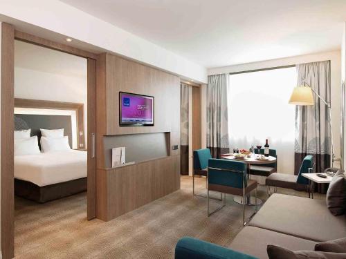a hotel room with a bed and a dining room at Novotel Fontainebleau Ury in Ury