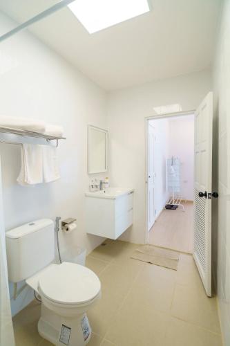 a white bathroom with a toilet and a sink at 4BR Pool Villa Sukhum in Phuket Town in Changwat Phuket