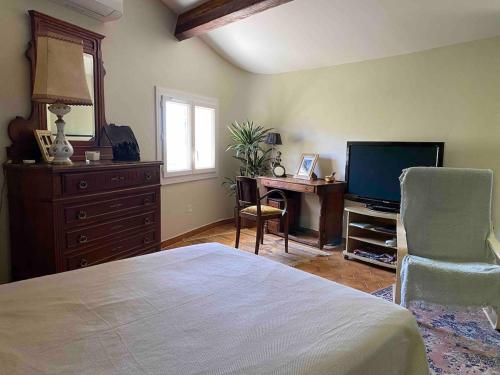 Un dormitorio con una cama, un escritorio y un televisor. en Bastidon, Petite bastide pour 2 avec bassin et jardin privé, en Crillon-le-Brave