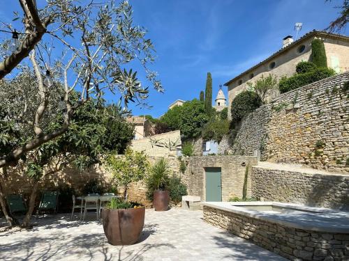 Un jardín con un muro de piedra y un patio. en Bastidon, Petite bastide pour 2 avec bassin et jardin privé, en Crillon-le-Brave