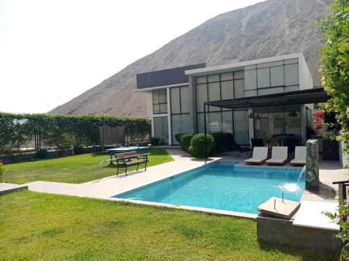 a house with a swimming pool in front of a mountain at Maya House Cieneguilla in Cieneguilla