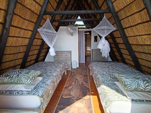 a bedroom with two beds in a thatched room at Cosy Cottage in Buffelspoort