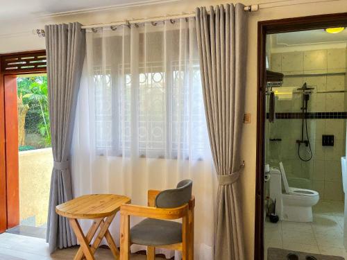 a table and a chair in a bathroom with a toilet at SKA The Boutique Naguru in Bukoto