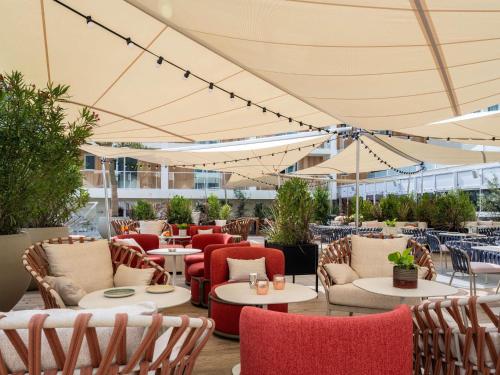 ラ・ロシェルにあるMercure La Rochelle Vieux Portのテーブル、椅子、パラソルのある屋外パティオ