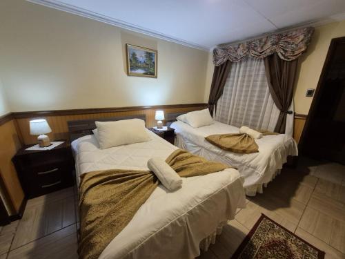 プエルト・ナタレスにあるHostal Oasisのベッドが2つと窓があるホテルの部屋
