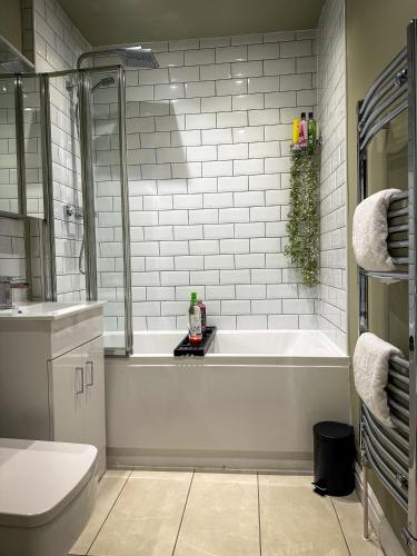 a white bathroom with a tub and a toilet at Warm & Cosy, First Floor 2 Bed Central Apartment in Harrogate