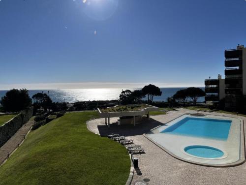 a swimming pool with chairs and the ocean in the background at Seaside one bedroom apartment with terraces, garage & swimming pool in Cascais