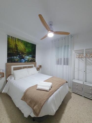 a bedroom with a white bed with a ceiling fan at Apartamento Rural Casa Mar in El Bosque