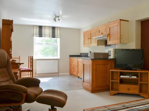 a kitchen with wooden cabinets and a flat screen tv at Brigham Farm Apartments in Keswick