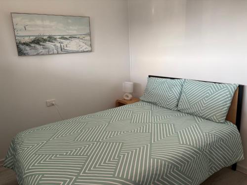 a bedroom with a bed and a picture on the wall at Caves Beach Holiday House in Caves Beach